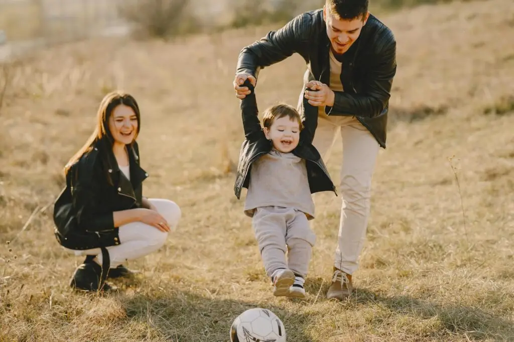 Family playing together in a sunny field while sharing outdoor experiences, connection, and joy